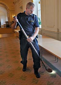 En polis undersöker området utanför ett av riksdagens mötesrum. Foto: Bertil Ericson/Scanpix