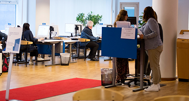 Människor sitter vid datorer på Arbetsförmedlingen