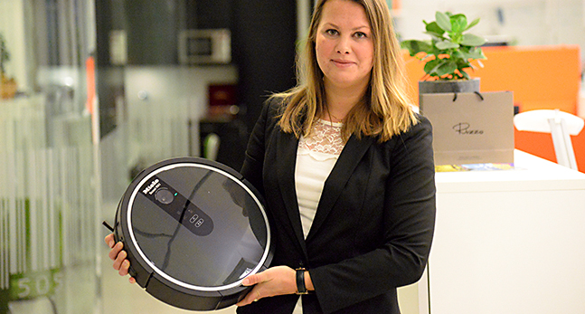 En kvinna håller upp en robotdammsugare.