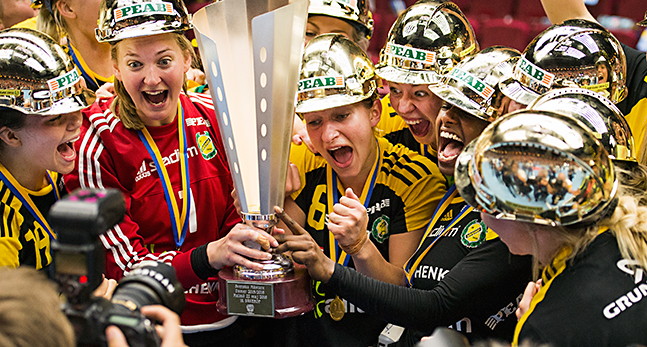 Handbollskvinnor i guldhattar lyfter en pokal och jublar.