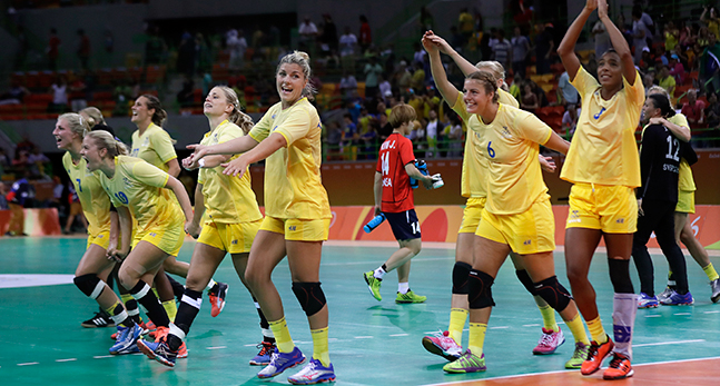Gulklädda handbollsdamer skrattar på planen efter vinsten mot Sydkorea.