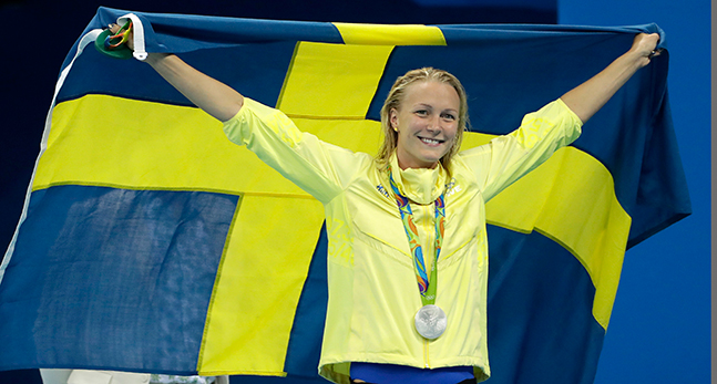 Sarah Sjöström håller upp en stor svensk flagga.