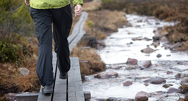 En person vandrar på en vandringsled. En spång längs med ett vattendrag.