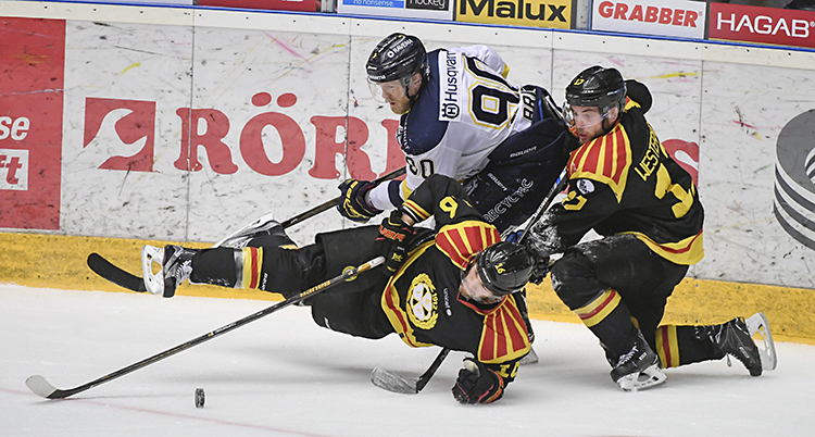 Tre spelare kämpar om pucken.