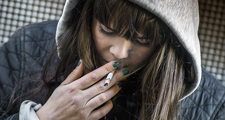 En ung tjej röker en cigarett