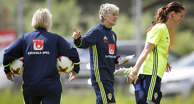 Pia Sundhage och två spelare som värmer upp.