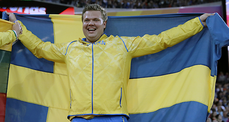 Daniel Ståhl skrattar och håller upp en svensk flagga.