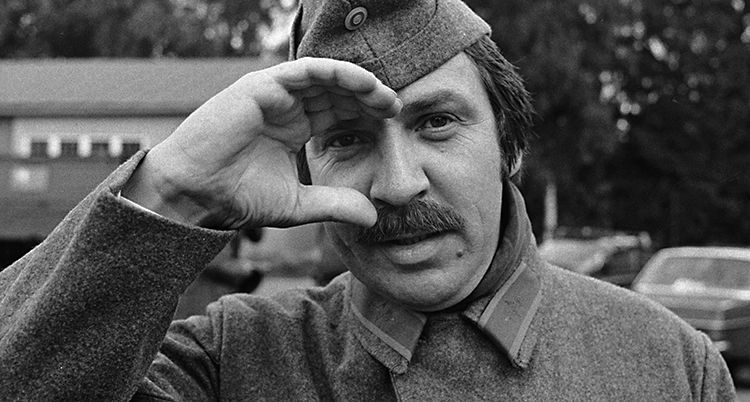 En svartvit bild på Janne Carlsson klädd i soldatkläder. Fotot är från filmen Repmånad.