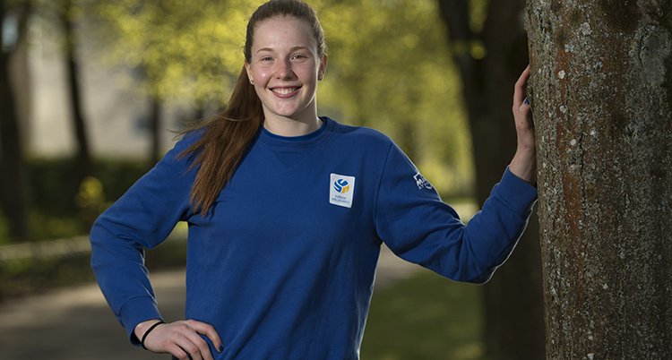Isabelle Haak står och ler vid ett träd.