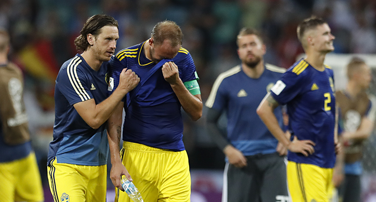 Ledsna svenska spelare på en fotbollsplan.