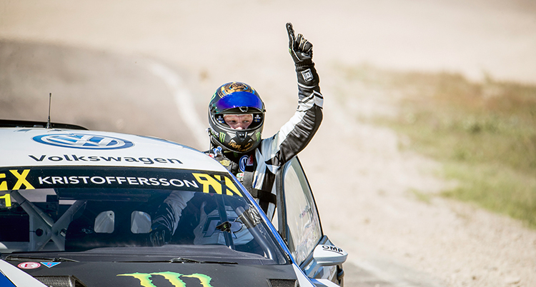 Johan Kristoffersson i hjälm och skinnställ tittar ut ur sin bil. Han sträcker en arm i luften i en slags segergest.