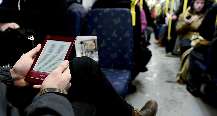 En man läser en e-bok i tunnelbanan