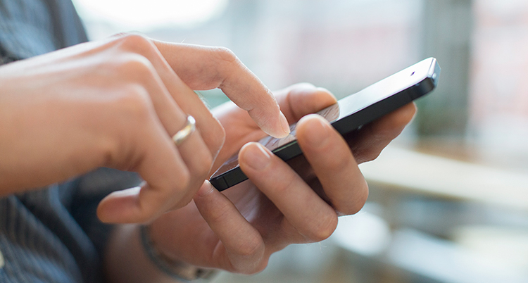 En hand som knappar på en mobiltelefon.