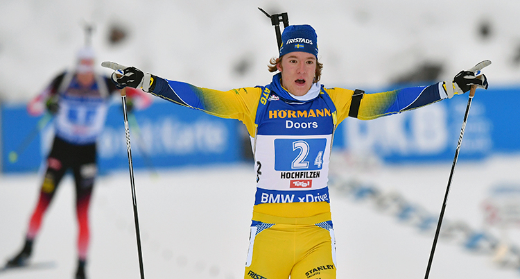 Svenska Sebastian Samulelsson i gul dräkt åker i mål med armarna utsträckta.