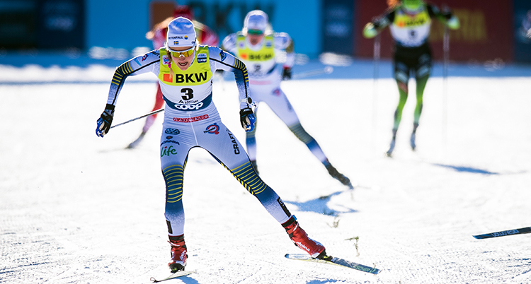 Stina Nilsson i vit dräkt på sina skidor.