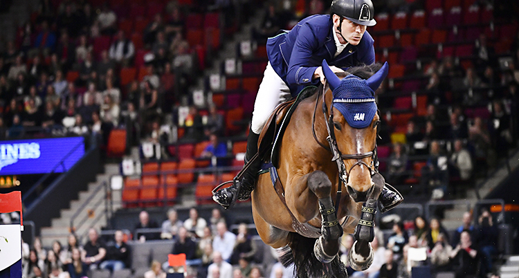 Peder Fredricson i blåa kläder på en brun häst