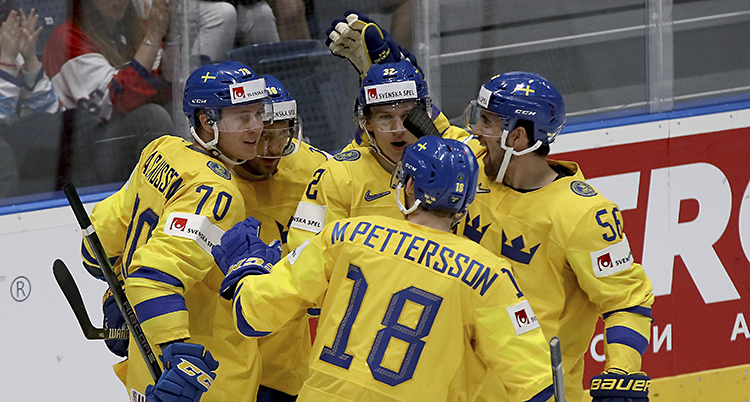 Spelare i Tre Kronor kramar om varandra på isen.