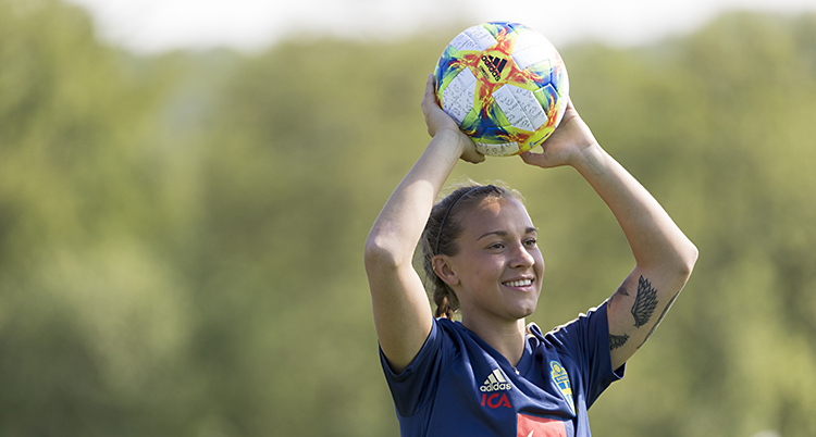 Julia håller bollen över huvudet och ska göra ett inkast. Hon ser glad ut.