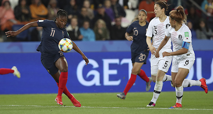 En fransk spelare tar emot bollen i luften. Två koreanskor är på väg att försöka stoppa henne