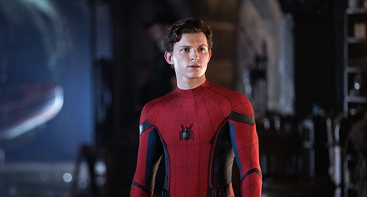 Skådepelaren Tom Holland står i ett rum och har en spindelmannendräkt på sig.
