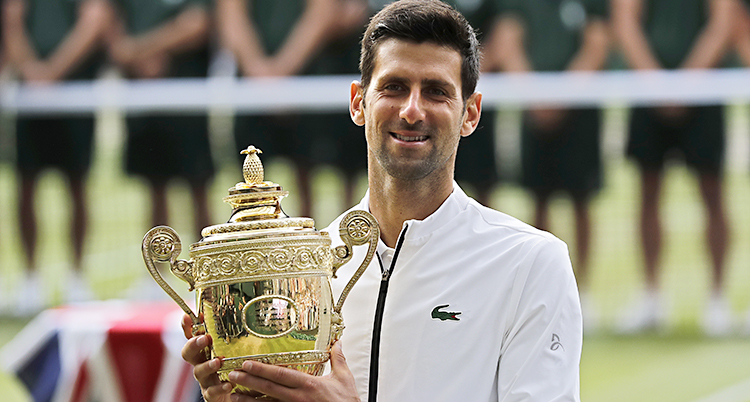 Tennisspelaren Novak Djokovic ler och står med en pokal.
