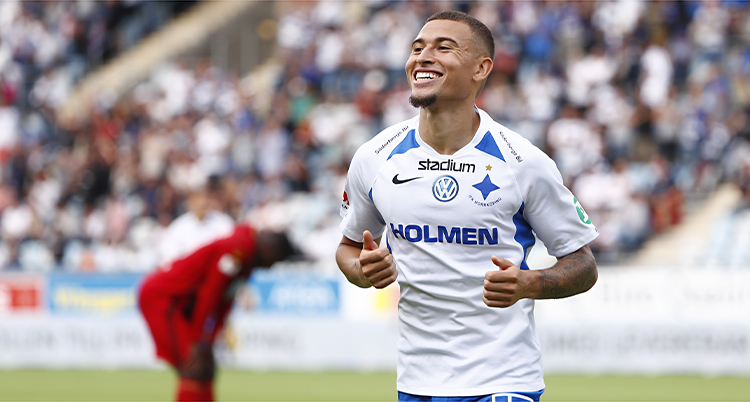 Jordan Larsson springer på en fotbollsplan och ler. Han har IFK Norrköpings tröja på sig.