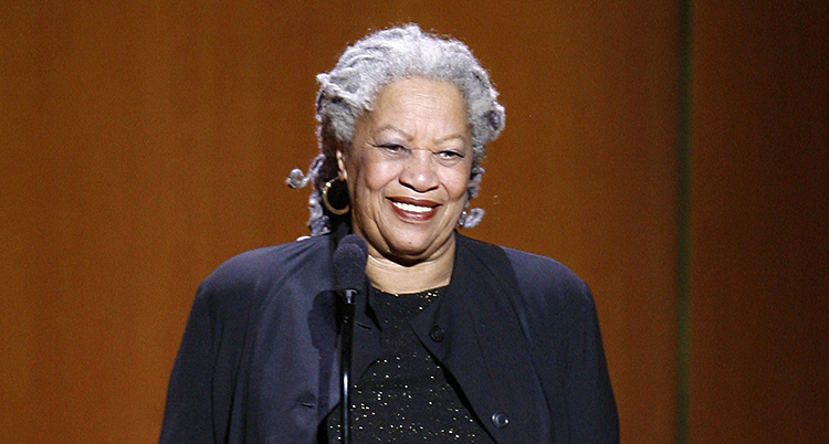 Toni Morrison ler. Hon står på en scen vid en mikrofon.