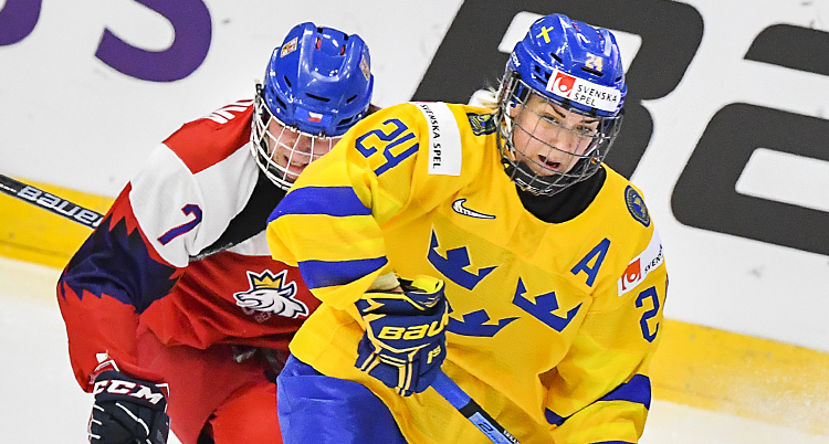 Närbild på Erika under en hockeymatch. Hon har en back bakomsig och verkar vara på väg att anfalla