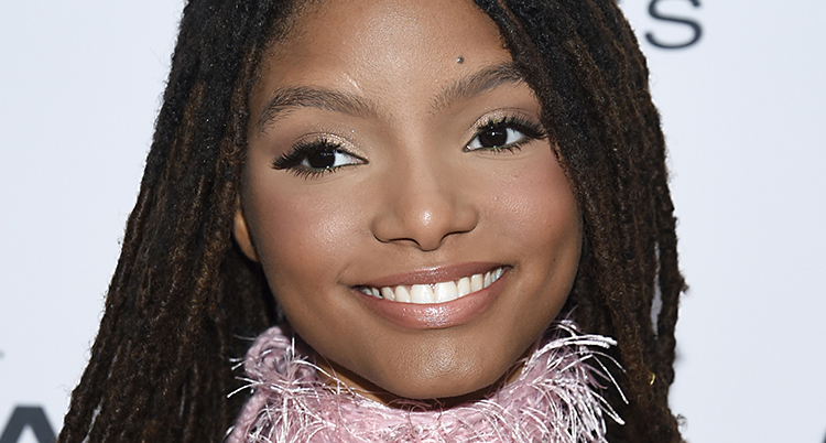 En närbild på skådespelaren Halle Bailey. Hon ler och har kläder med rosa krage.
