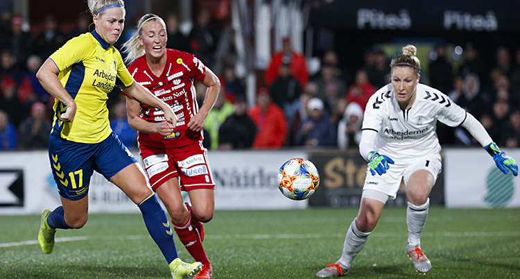 En spelare i gul och blå dräkt jagas av en röd spelare från Piteå och målvakten i vit dräkt.
