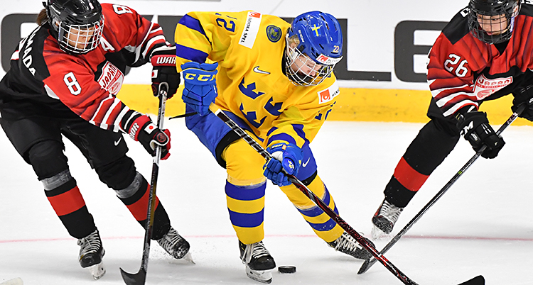 En svensk spelare kämpar om pucken med spelare i röda tröjor.