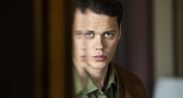 Bill Skarsgård ser allvarlig ut, han har blåa ögon och brunt välkammat hår
