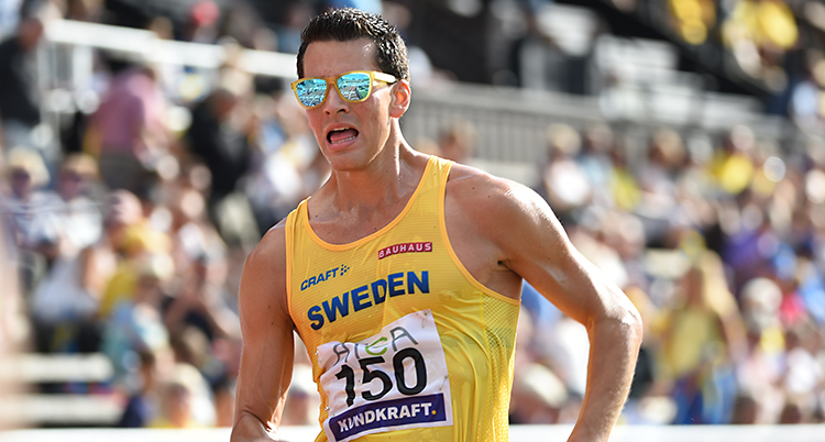 En man som tävlar i sporten gång. Han har solglasögon på sig och ett gult linne där det står Sweden.