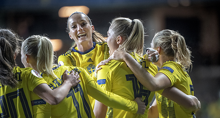 Svenska spelare i gula tröjor kramnar om Kosovare Asllani.