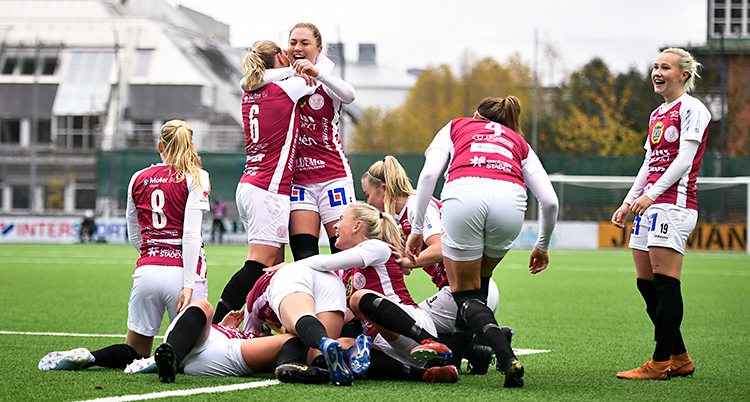En bild från en match i fotboll. Flera spelare ligger på planen och kramas. Andra spelare står upp och kramas. De har vita shorts och röda tröjor med vita ärmar.