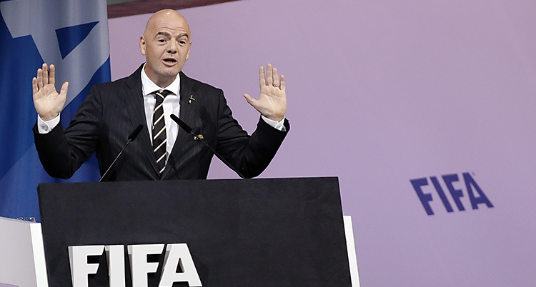 Gianni Infantino pratar. Han har båda händerna i luften. Han står bakom en skylt som det står Fifa på.