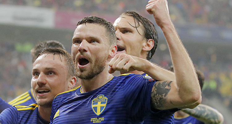 Marcus jublar och höjer näven i luften. Man ser hans ansikte och andra spelare kramar honom bakifrån.