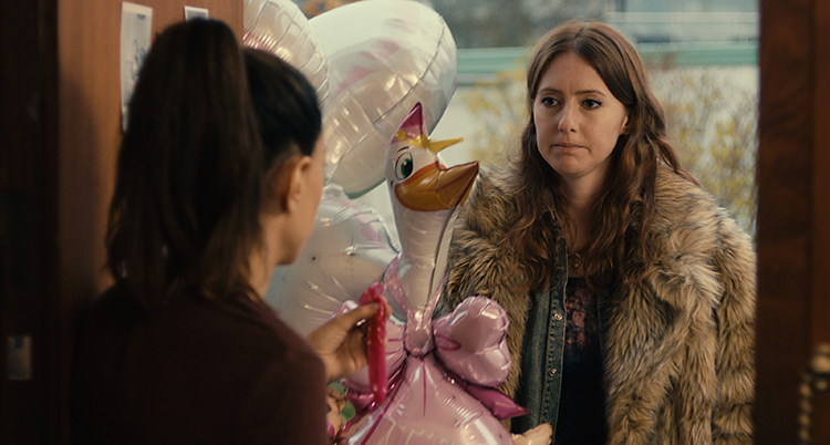 Niki står med färgglada ballonger i dörren hos sin kompis