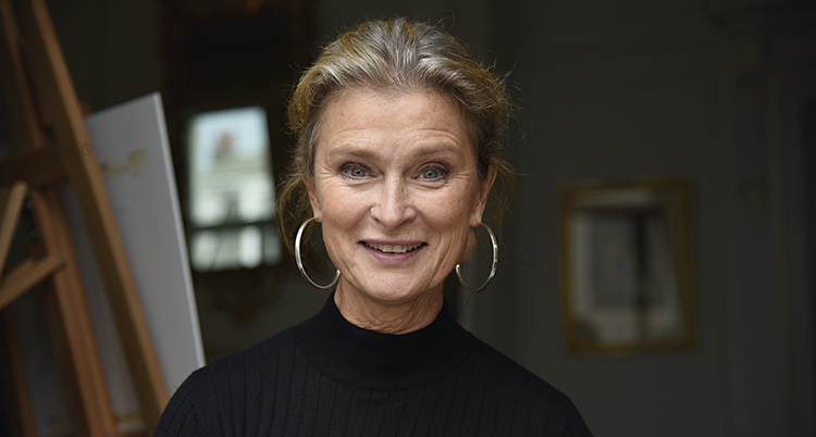Hon ser glad ut, har svart tröja och silverringar i öronen
