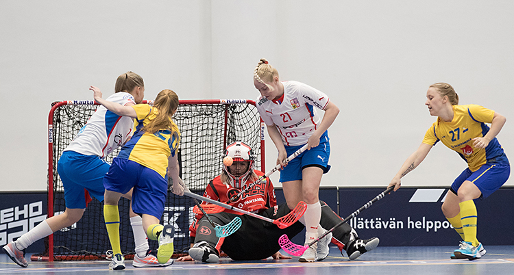 Sveriges damer spelar en match i innebandy mot Tjeckien. Två spelare från varje lag kämpar om bollen framför en av målvakterna.