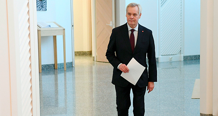 Finlands statsminister Antti Rinne går med ett papper i handen. Han har kostym och grått hår.