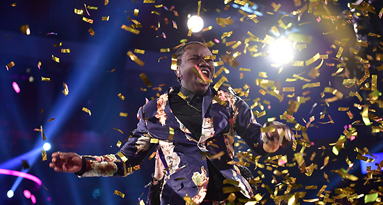 Tusse skriker av glädje och de ramlar guld-konfetti över honom