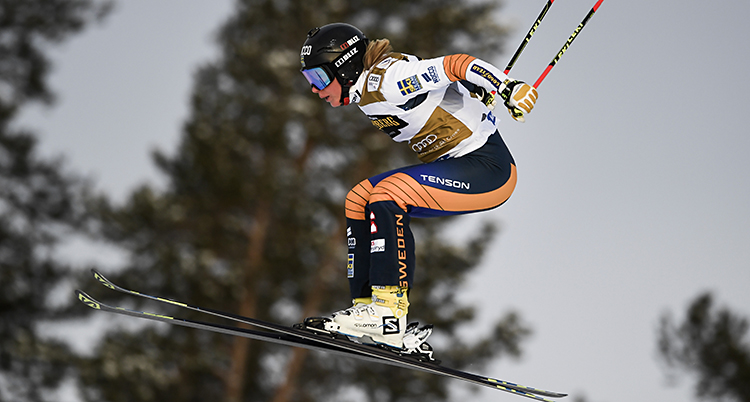 Hon hoppar i luften med korta skidor