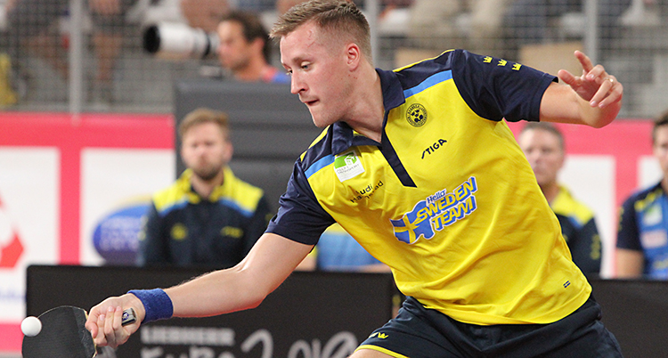Falck i gul landslagströja under en match. Han slår bollen med sin racket.