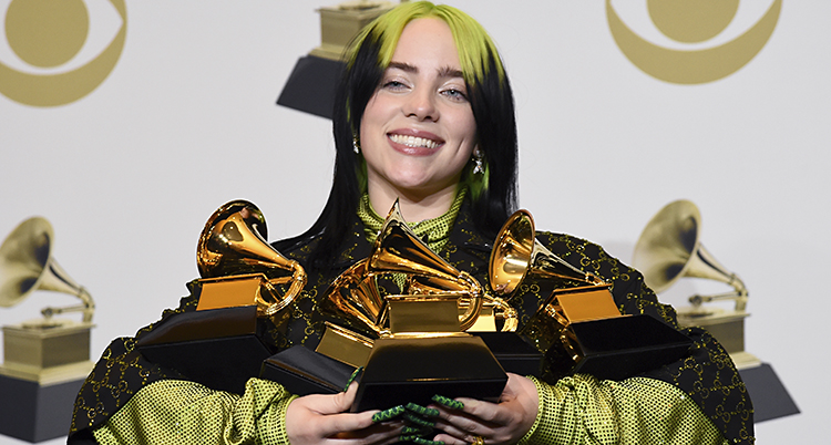 Billie Eilish ler med fyra guldfärgade priser i famnen.