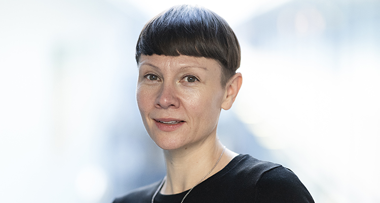 Karin har kort brunt hår och lugg. Hon har en svart tröja på sig.