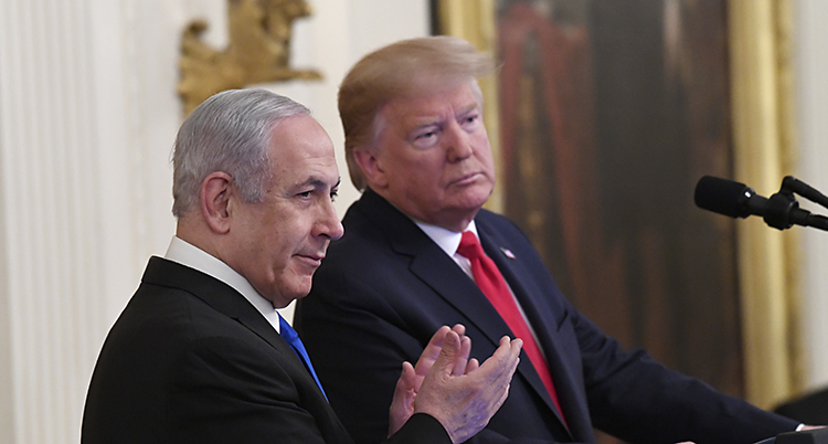 Netanyahu klappar i händer. Han står bredvid Trump som lutar sig åt Netanyahus håll.