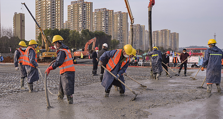 Människor står med stövlar i cement och försöker att jämna till den.