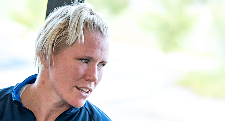 Jenny Fransson tittar till höger. Hon har blont hår i en tofs. Hon sitter framför ett fönster.