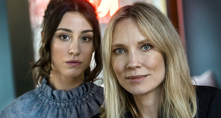 Två kvinnor tittar in i kameran. Kvinnan till vänster heter Madeleine och har långt mörkt hår. Kvinnan till höger heter Moa och har långt ljust hår.